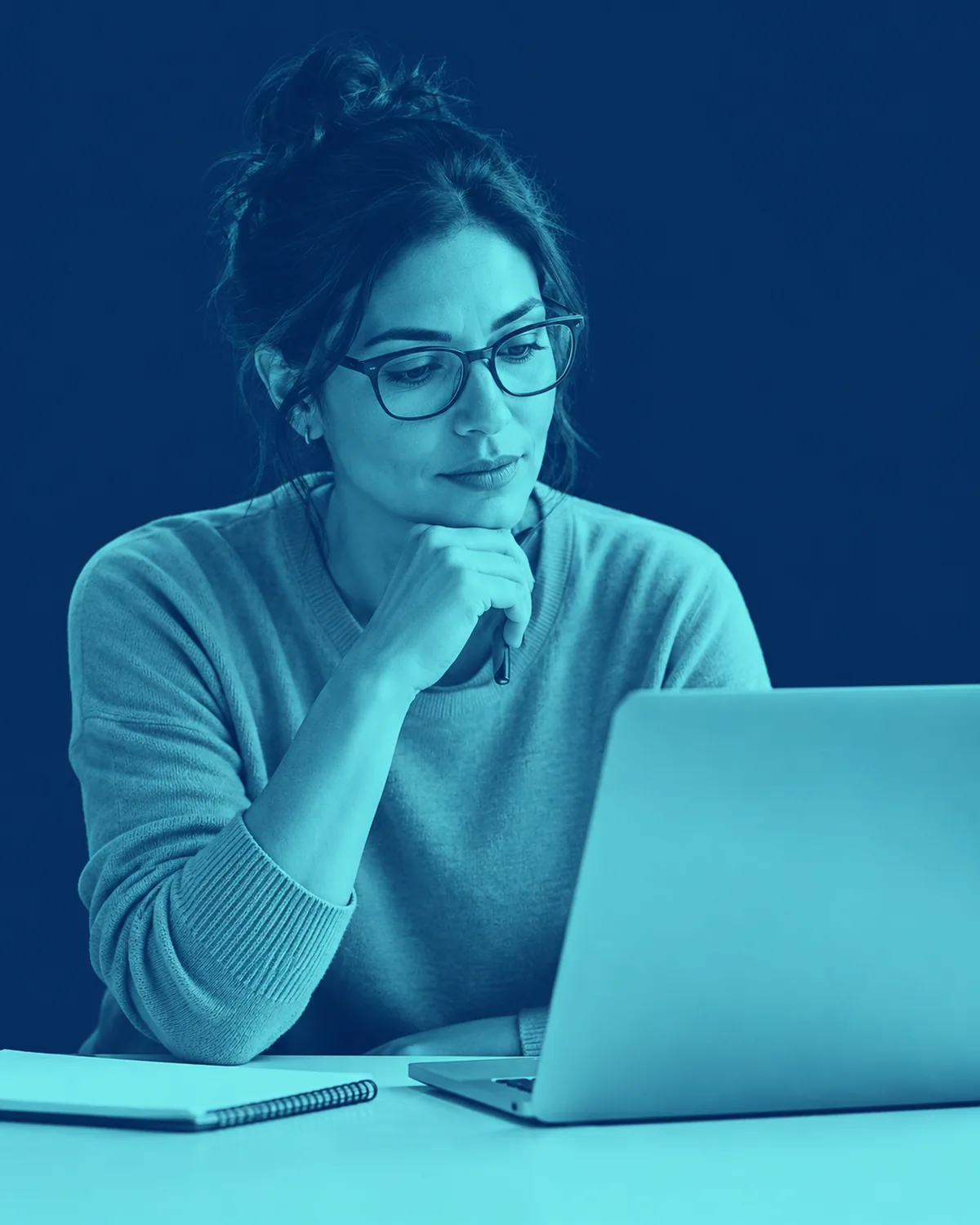 A teacher considering something on her laptop screen.